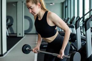 A young girl in black sportswear is engaged in the gym with dumbbells. Fitness club concept. photo