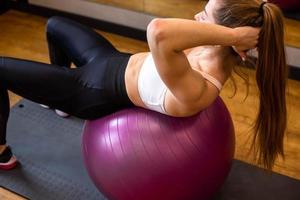 Young woman in sportswear is engaged on fitball in indoor gym photo