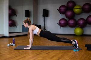 Young woman in sportswear doing stretching in indoor gym photo