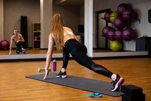 Young woman in sportswear doing stretching in indoor gym photo