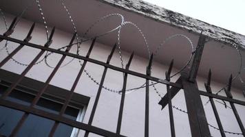 Barbed wire enclosure outside a building with metal grill.