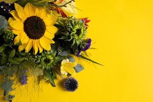 Beautiful bouquet of flowers with a sunflower on a bright yellow background with copy space. photo