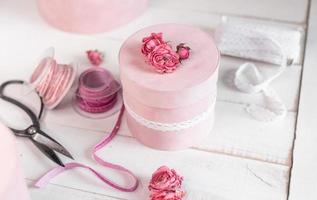 Beautiful pink round gift wrapping is decorated with narrowed roses. Romantic packaging concept photo