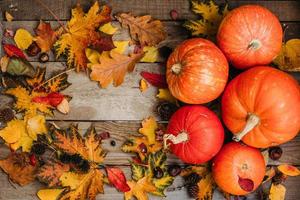 Pumpkins with fall leaves over wooden background. Orange halloween pumpkins in autumm composition. photo