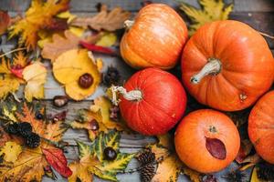Pumpkins with fall leaves over wooden background. Orange halloween pumpkins in autumm composition. photo