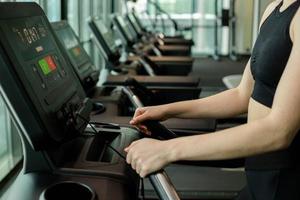 Happy athletic woman jogging on treadmills in a gym. photo