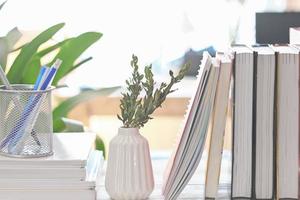 Close up view of workspace with books and ceramic vase on white desk. learning and education. cozy house working place. photo