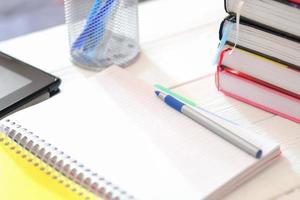 school exercise copybook or notepad with ballpoint pen on wooden table. stack of books. back to school concept photo