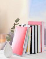 books and notebooks in a row and ceramic vase with dry eucalyptus branch. study and learning, reading and education concept. vertical shot. photo