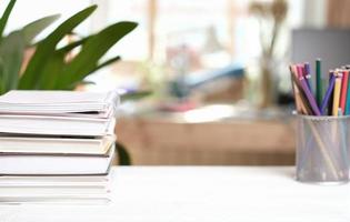 espacio de trabajo en casa con libros y lápices de colores sobre una mesa blanca. copie el espacio para la colocación del producto. aprendizaje en casa o educación a distancia. foto