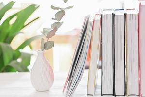 vista de cerca del espacio de trabajo con libros y jarrón de cerámica en el escritorio blanco. aprendizaje y educación. acogedor lugar de trabajo de la casa. foto