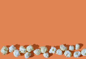 salty popcorn on orange background. copy space. photo