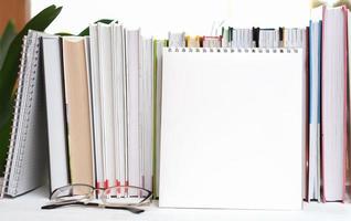 blank notebook next to a row of books and eyeglasses. copy space, template for text photo