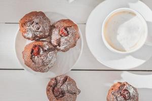 dulce de fin de semana por la mañana, muffins de café y bayas, pasteles caseros con azúcar en polvo foto