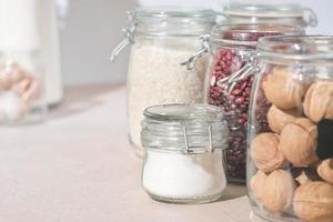 glass jars with grains, nuts and sugar on a kitchen table. sustainable home grocery storage and zero plastic house. eco friendly kitchen. photo