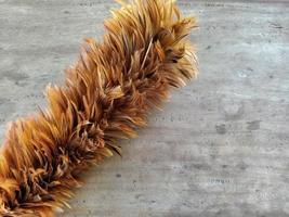 feather duster on brown wooden background with copy space photo