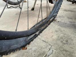 Neumático de bicicleta viejo y polvoriento plano en el suelo foto