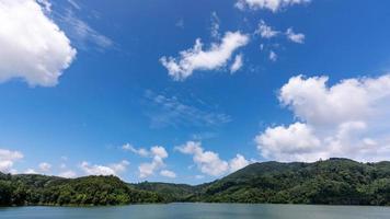 White clouds in blue sky over green mountains covered with rainforests trees Beautiful landscape of Mountain and Lake with reflex in the water scenery beautiful view with blue sky and white clouds. photo