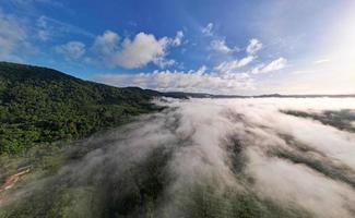 Aerial view Panorama of flowing fog waves on mountain tropical rainforest,Bird eye view image over the clouds Amazing nature background with clouds and mountain peaks in Thailand photo