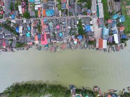 Aerial view top view of the fisherman village with fishing boats and house roof at the pier in suratthani Thailand. Panorama high angle view photo