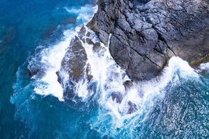 Aerial view Top down seashore big wave crashing on rock cliff Beautiful dark sea surface in sunny day summer background Amazing seascape top view seacoast at Phuket Thailand photo