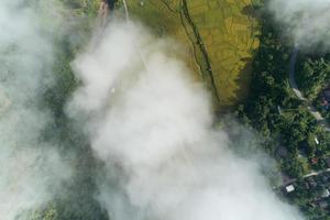 Aerial view drone shot of flowing fog waves on mountain tropical rainforest,Bird eye view image over the clouds Amazing nature background with clouds and mountain peaks in Nan Thailand. photo