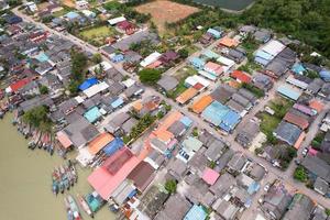 Aerial view top view of the fisherman village with fishing boats and house roof at the pier in suratthani Thailand. high angle view photo