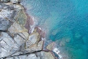 vista aérea de arriba hacia abajo de la ola de la costa rompiendo en la orilla del mar hermosa superficie turquesa del mar en un día soleado día de buen tiempo fondo de verano foto