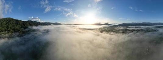 Aerial view Panorama of flowing fog waves on mountain tropical rainforest,Bird eye view image over the clouds Amazing nature background with clouds and mountain peaks in Thailand photo