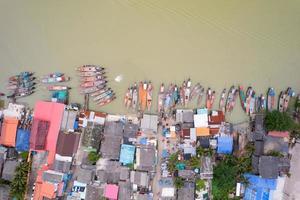 Aerial view top view of the fisherman village with fishing boats and house roof at the pier in suratthani Thailand. high angle view photo