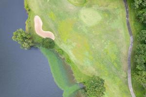 Aerial view drone shot of beautiful green golf field fairway and putting green Top down image for sport background and travel nature background Amazing view photo