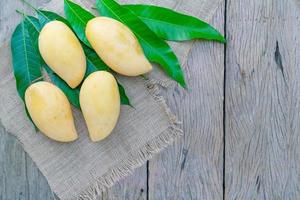 Mango with leaves on wooden table background photo