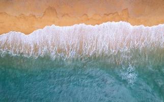 vista aérea playa de arena y olas hermoso mar tropical en la mañana imagen de la temporada de verano por vista aérea toma de drones, vista de ángulo alto de arriba hacia abajo olas del mar foto