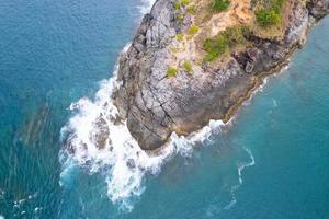 Aerial view Top down seashore big wave crashing on rock cliff Beautiful dark sea surface in sunny day summer background Amazing seascape top view seacoast at Phuket Thailand photo