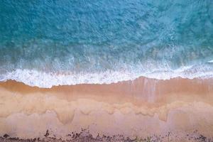 vista aérea playa de arena y olas hermoso mar tropical en la mañana imagen de la temporada de verano por vista aérea toma de drones, vista de ángulo alto de arriba hacia abajo olas del mar foto