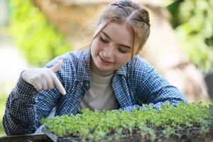 pequeña granjera en el jardín regando plantas y cosechando verduras. foto