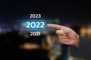 Businessman hand touching 2022 year number on virtual screen concept digital trends,industry and business trend. copy space. photo