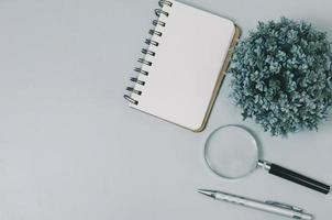 Top view blank notebook and magnifying glass pen on copy space gray background. photo