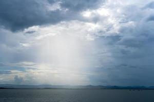 Kra Siew Dam, a tourist attraction in Kanchanaburi, Thailand, the sky is overcast, the rain is about to fall and the light from the sun shines through the clouds. photo