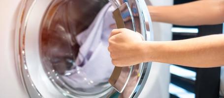 Housewife Woman hand holding clothes inside Washing Machine in laundry room photo