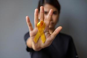 día de prevención del suicidio, mes de concientización sobre el sarcoma, los huesos, la vejiga y el cáncer infantil, cinta amarilla para apoyar a las personas que viven y están enfermas. cuidado de la salud infantil y concepto del día mundial del cáncer foto