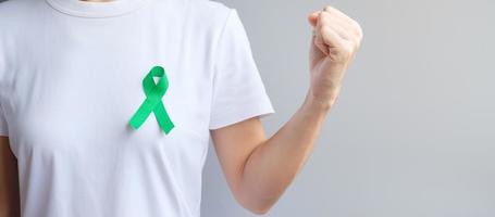 cinta verde para el mes de concientización sobre el hígado, las vesículas biliares, las vías biliares, el cuello uterino, el cáncer de riñón y el linfoma. concepto de salud y día mundial del cáncer foto