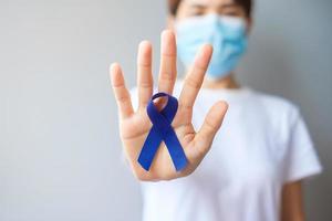 March Colorectal Cancer Awareness month, Woman holding dark Blue Ribbon for supporting people living and illness. Healthcare, hope and World cancer day concept photo