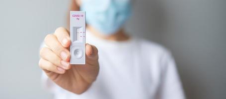 mujer sosteniendo un kit de prueba rápida de antígeno con resultado negativo durante la prueba de hisopo covid-19. coronavirus auto nasal o prueba casera, concepto de bloqueo y aislamiento del hogar foto