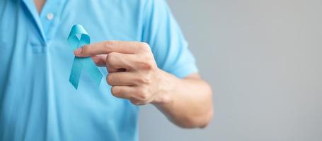 noviembre mes de concientización sobre el cáncer de próstata, hombre con camisa azul con la mano sosteniendo una cinta azul para apoyar a las personas que viven y están enfermas. cuidado de la salud, hombres internacionales, padre y concepto del día mundial del cáncer foto