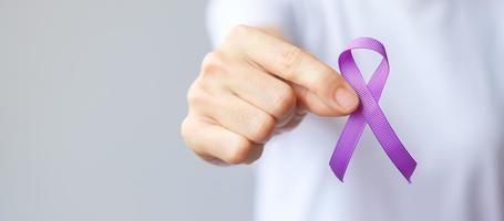 Hand holding purple Ribbon for Pancreatic, Esophageal, Testicular cancer, world Alzheimer, epilepsy, lupus, Sarcoidosis, Fibromyalgia and domestic violence Awareness month. World cancer day concept photo