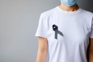 cinta negra para el melanoma y el cáncer de piel, mes de concientización sobre lesiones por vacunas, dolor y descanse en paz. salud y concepto racista foto