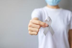 Brain Cancer Awareness month, woman hand holding grey color Ribbon for supporting people living. Healthcare and World cancer day concept photo