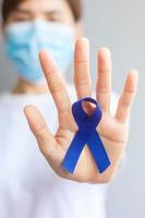 March Colorectal Cancer Awareness month, Woman holding dark Blue Ribbon for supporting people living and illness. Healthcare, hope and World cancer day concept photo