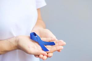 March Colorectal Cancer Awareness month, Woman holding dark Blue Ribbon for supporting people living and illness. Healthcare, hope and World cancer day concept photo